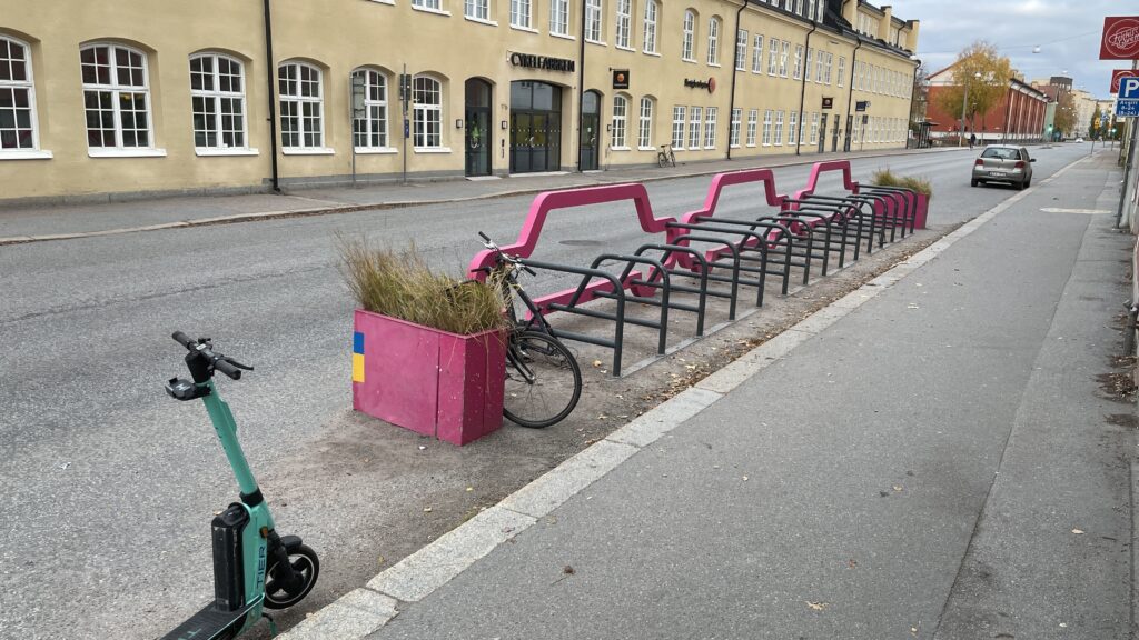Cykelhage, cykelställ med bil i profil som avgränsar mot körbanan